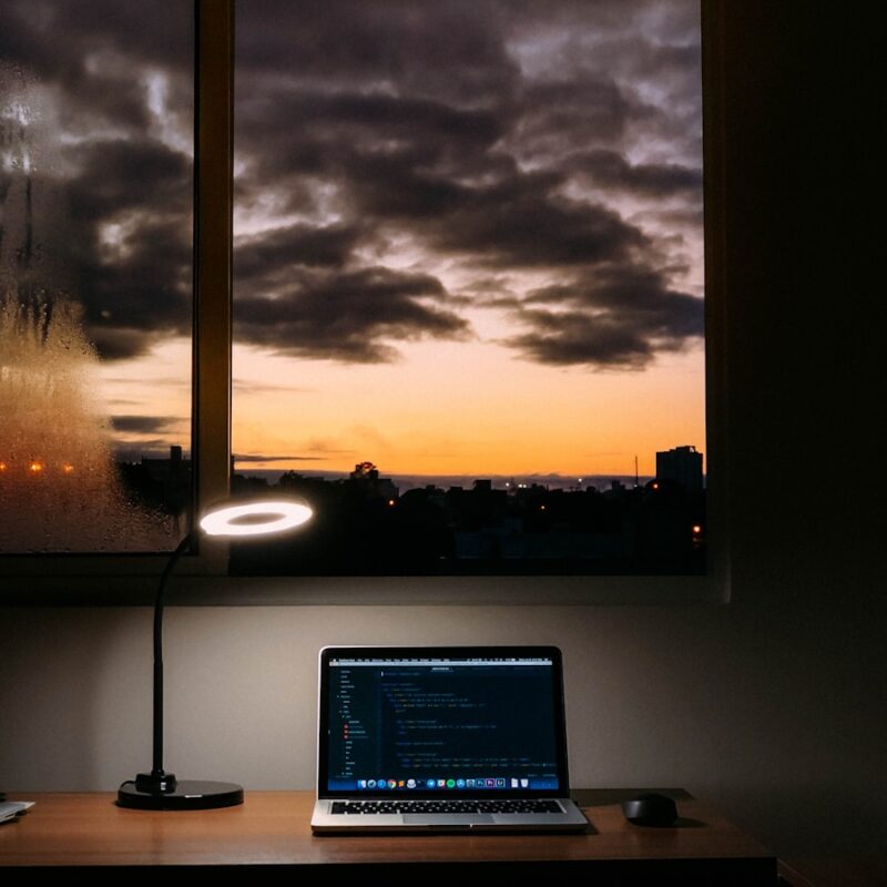 turned on laptop on desk near window